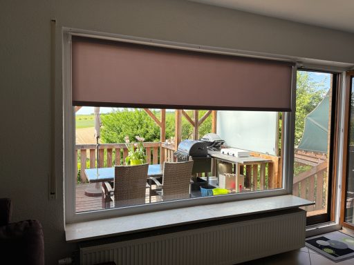Fenster mit Rollläden, Blick auf Terrasse und Grill.