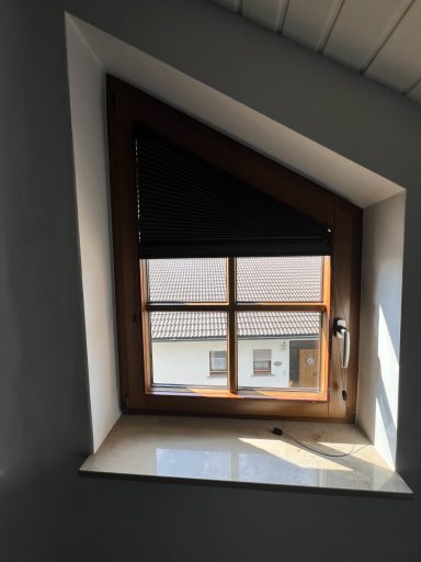 Dreieckiges Fenster mit Holzrahmen und Rolladen, Tageslicht fällt hinein.
