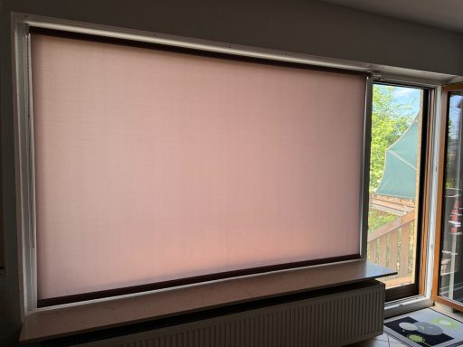 Helle Fenster mit einem zurückgezogenen, beige Rolladen und sichtbarem Licht draußen.