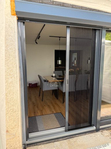 Türe mit Schiebetür in ein helles Zimmer mit Tisch und Stühlen.