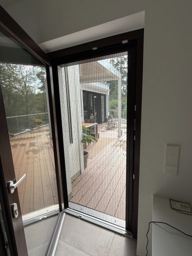 Offene Tür mit Blick auf eine Terrasse und angrenzende Wohnräume.