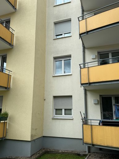 Fassade eines Wohngebäudes mit gelben Balkonen und Fenstern.