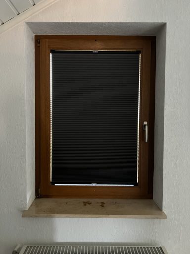 Ein Fenster mit einem schwarzen Rollos und einem breiten Fensterbrett aus Stein.