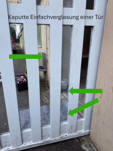 Kaputte Einfachverglasung einer Tür mit sichtbaren Rissen und Beschädigungen.